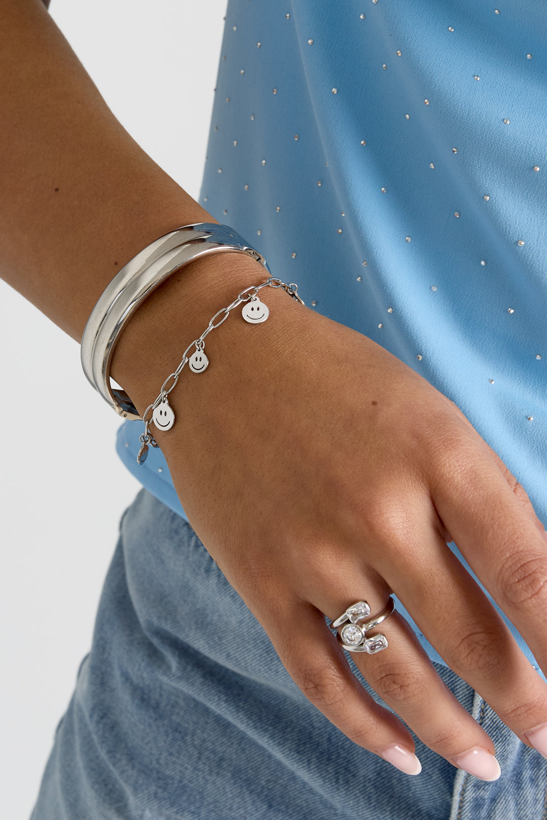 Happy Face Vibe: Silver charm bracelet with smiley faces, stacked with a sleek silver bangle and a modern crystal ring.