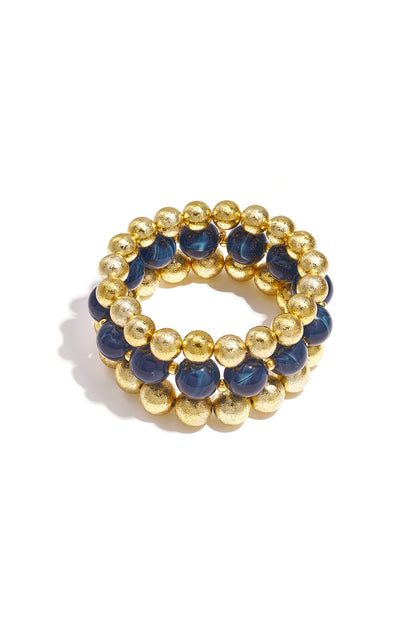 Set of three beaded bracelets with navy blue marbled beads and textured gold spheres on white background