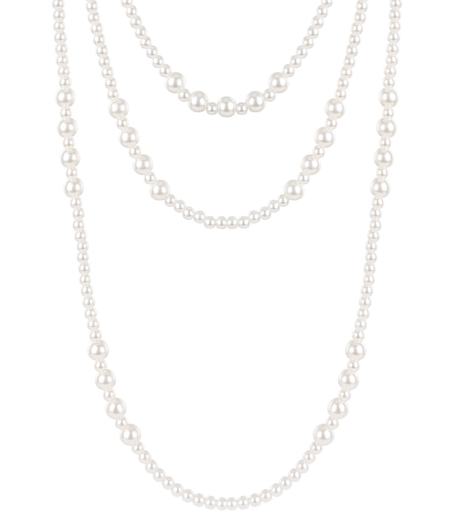Close-up of a layered pearl necklace featuring three strands of varying sizes of artificial pearls on white background