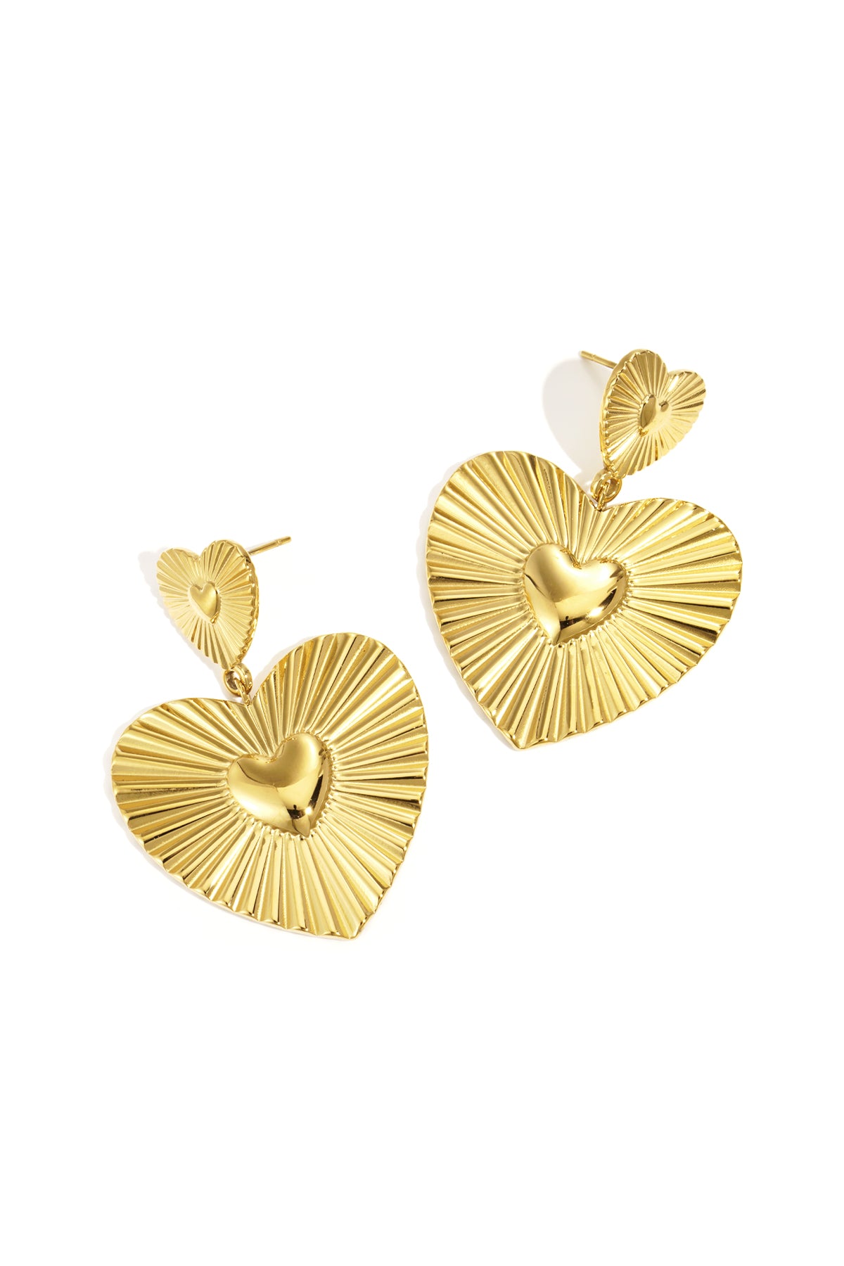 Pair of gold heart-shaped drop earrings with grooved texture and shiny center hearts on white background
