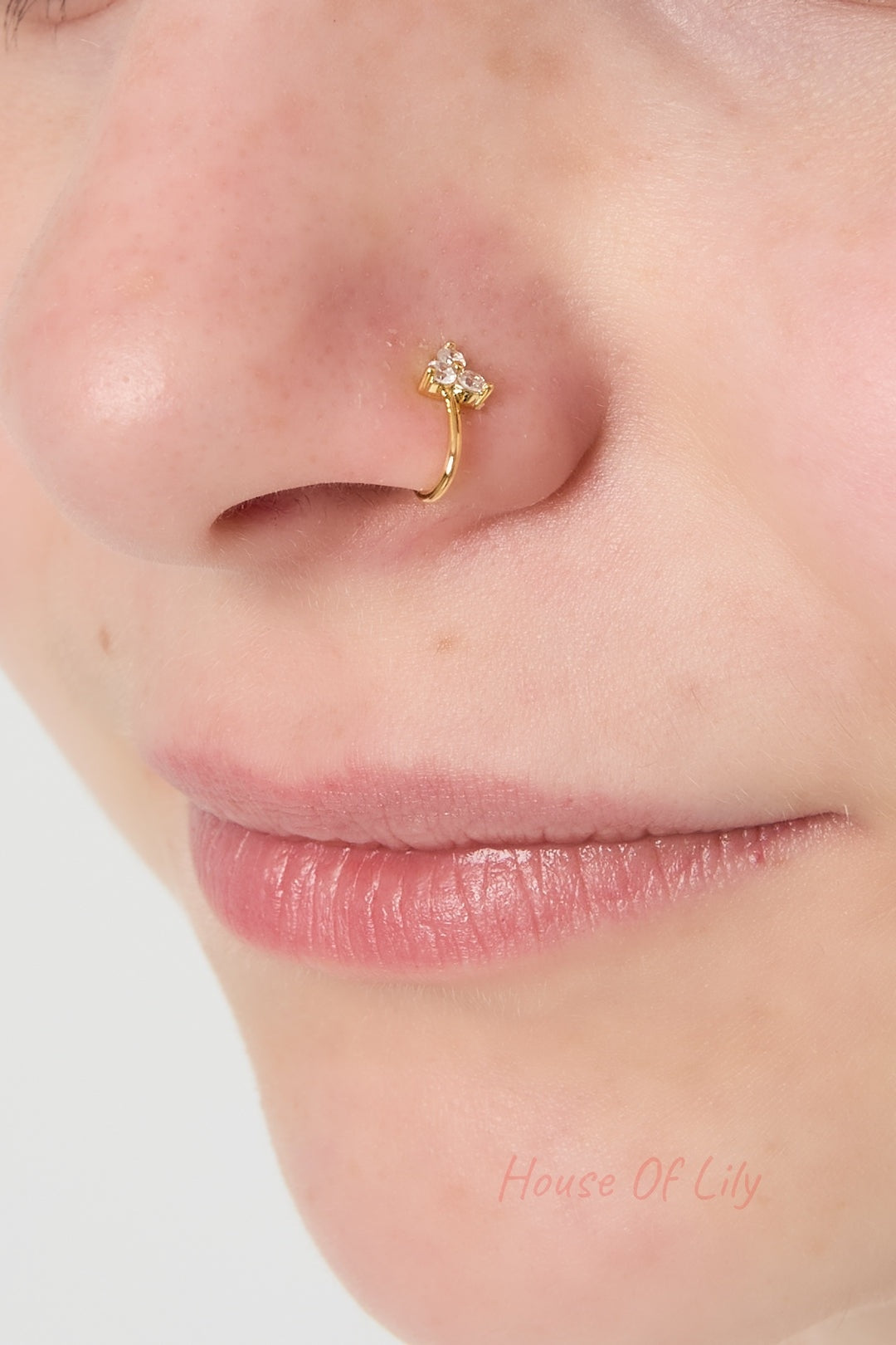 Close-up of a woman's nose wearing the gold nose cuff with three sparkling zircon stones