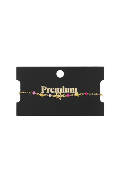Gold-tone star charm bracelet with pink and white beads on a black retail display card.