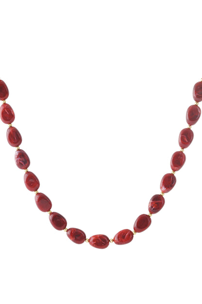 Red acrylic beaded necklace with gold spacer beads laid flat on white background