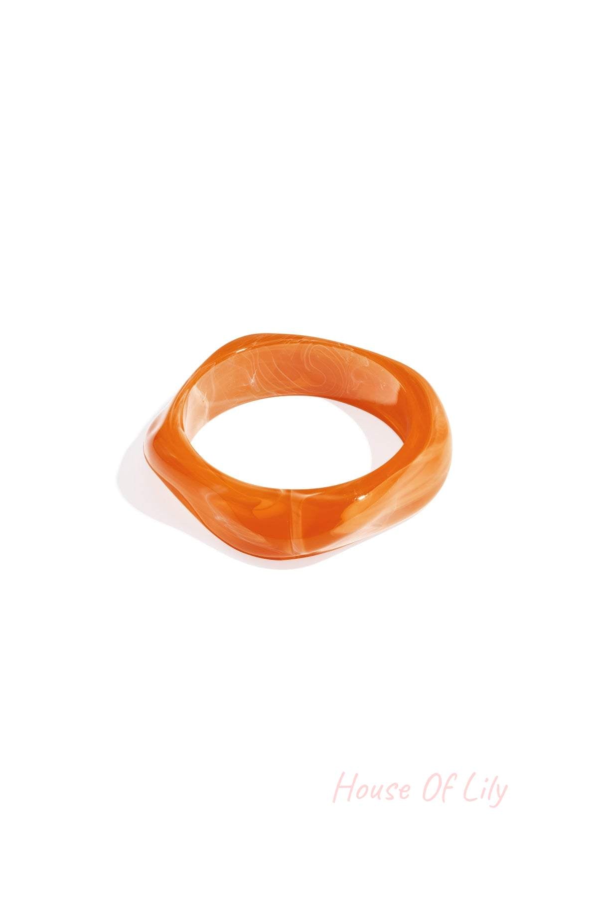Single orange acrylic bangle with a soft wavy square shape on white background