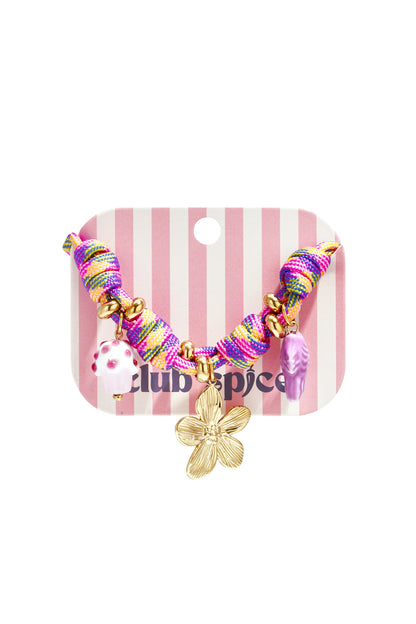 Close-up of multicolor rope charm bracelet with gold flower, cupcake and fish charms displayed on striped pink and white card