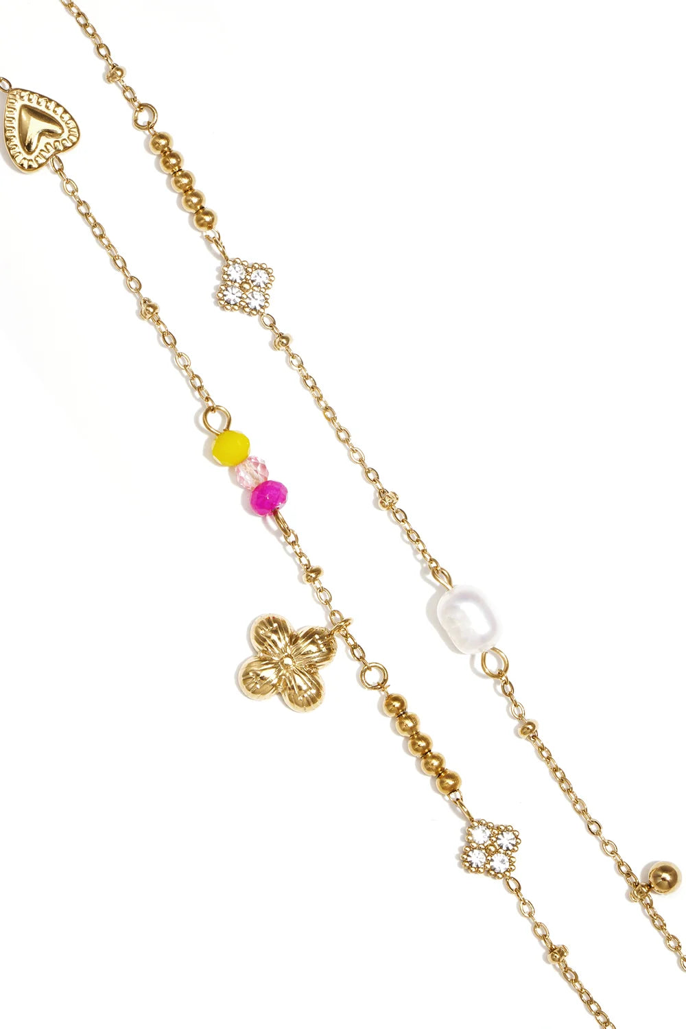 Gold chain charm bracelet stack featuring heart, clover, and floral charms with colorful beads, pearls, and crystals.