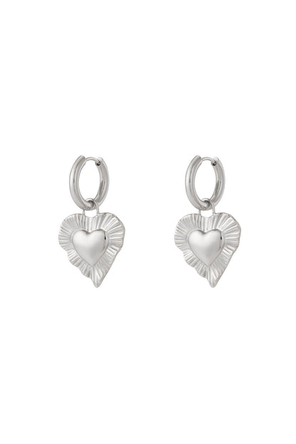 Pair of silver drop earrings with radiant heart-shaped charms featuring a textured fluted border on white background.