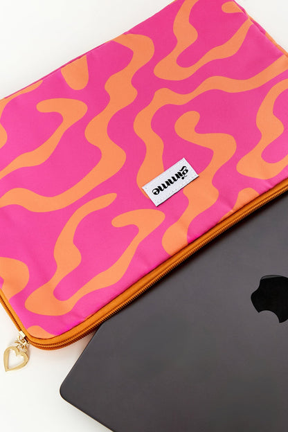 Close-up of pink and orange wavy patterned laptop sleeve partially open showing a black laptop inside, with heart-shaped zipper pull