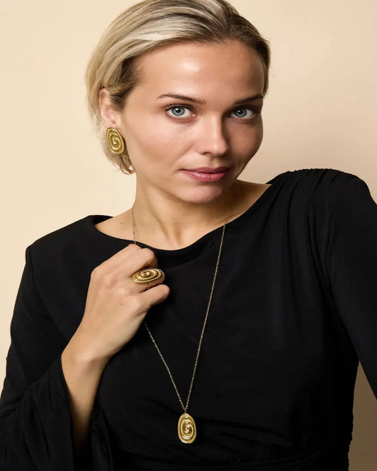 Woman wearing gold jewelry against a beige background
