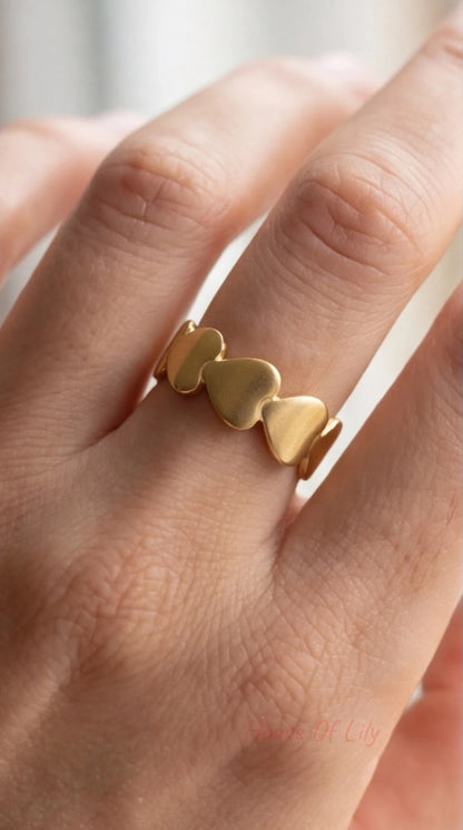 Gold heart-shaped ring on a person's finger with a blurred background