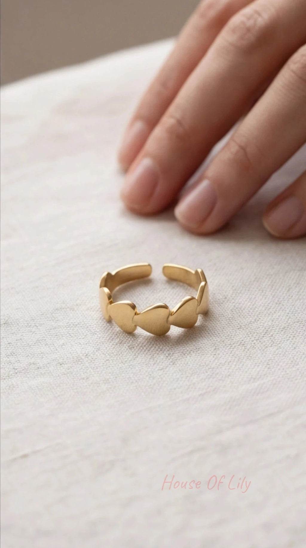Gold ring on a light fabric surface with a hand in the background