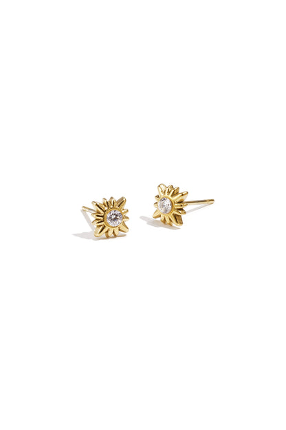 Pair of gold sunburst stud earrings with central clear rhinestones on white background