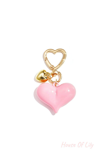 Single light pink acrylic heart bag charm with gold heart clasp and mini gold heart pendant on white background