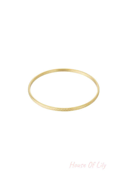 Gold textured bangle with fine etched pattern on white background
