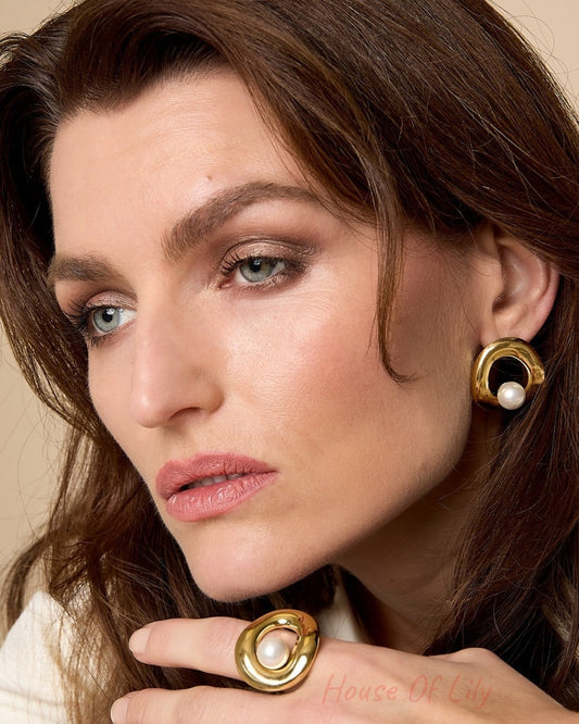 Close-up of woman wearing gold-tone circle pearl stud earrings and matching ring, showcasing youthful boutique style