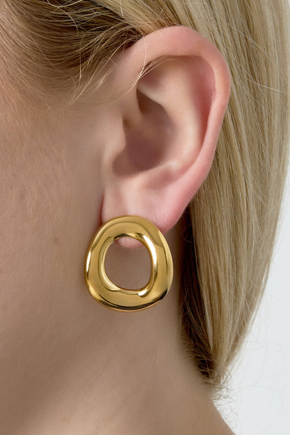 Close-up view of gold irregular hoop earring worn on woman’s ear showcasing lightweight and unique design