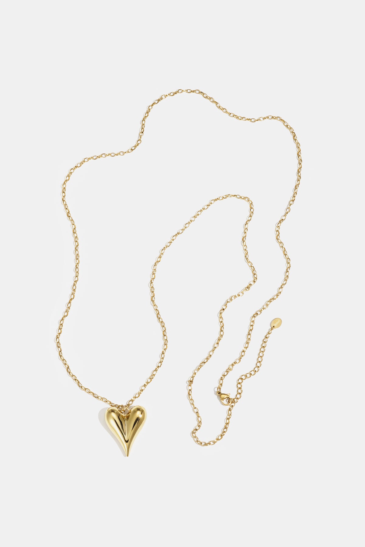 Gold heart pendant on a delicate gold chain necklace laid flat on white background