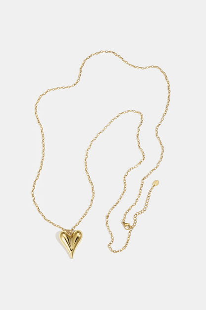 Gold heart pendant on a delicate gold chain necklace laid flat on white background