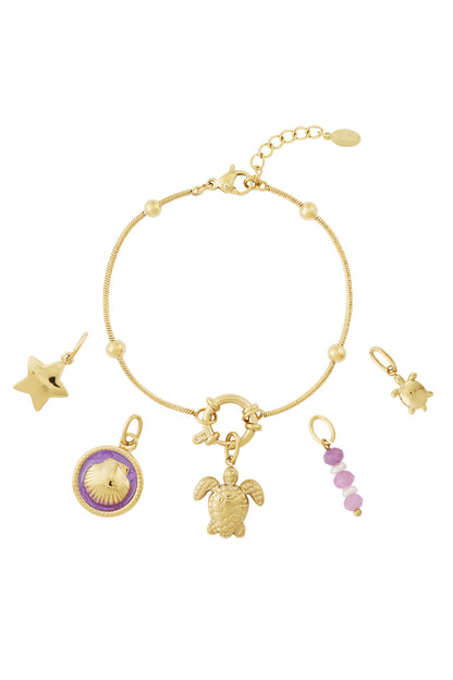 Gold charm bracelet with turtle, star, shell and pink bead charms laid out with charms detached