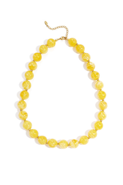 Marbled yellow round beaded necklace with gold spacers and a gold chain clasp on a white background.