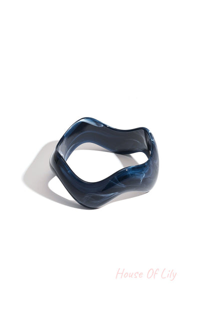 Blue marbled acrylic bangle with organic wavy edges on white background