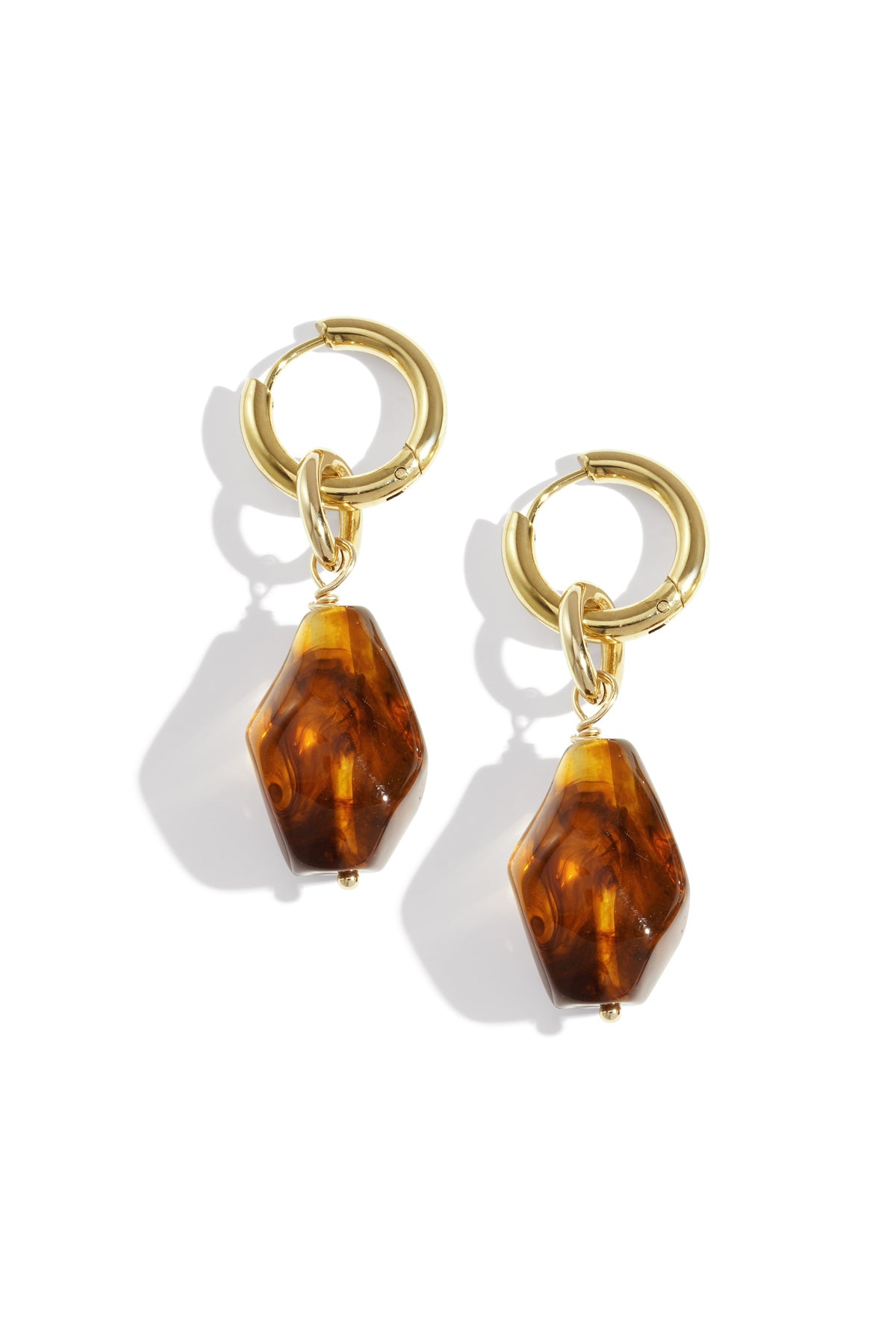 Pair of gold hoop drop earrings with irregular coffee brown acrylic charms on white background