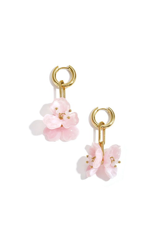 Pair of gold-tone drop earrings with pink acrylic flower pendants on a white background