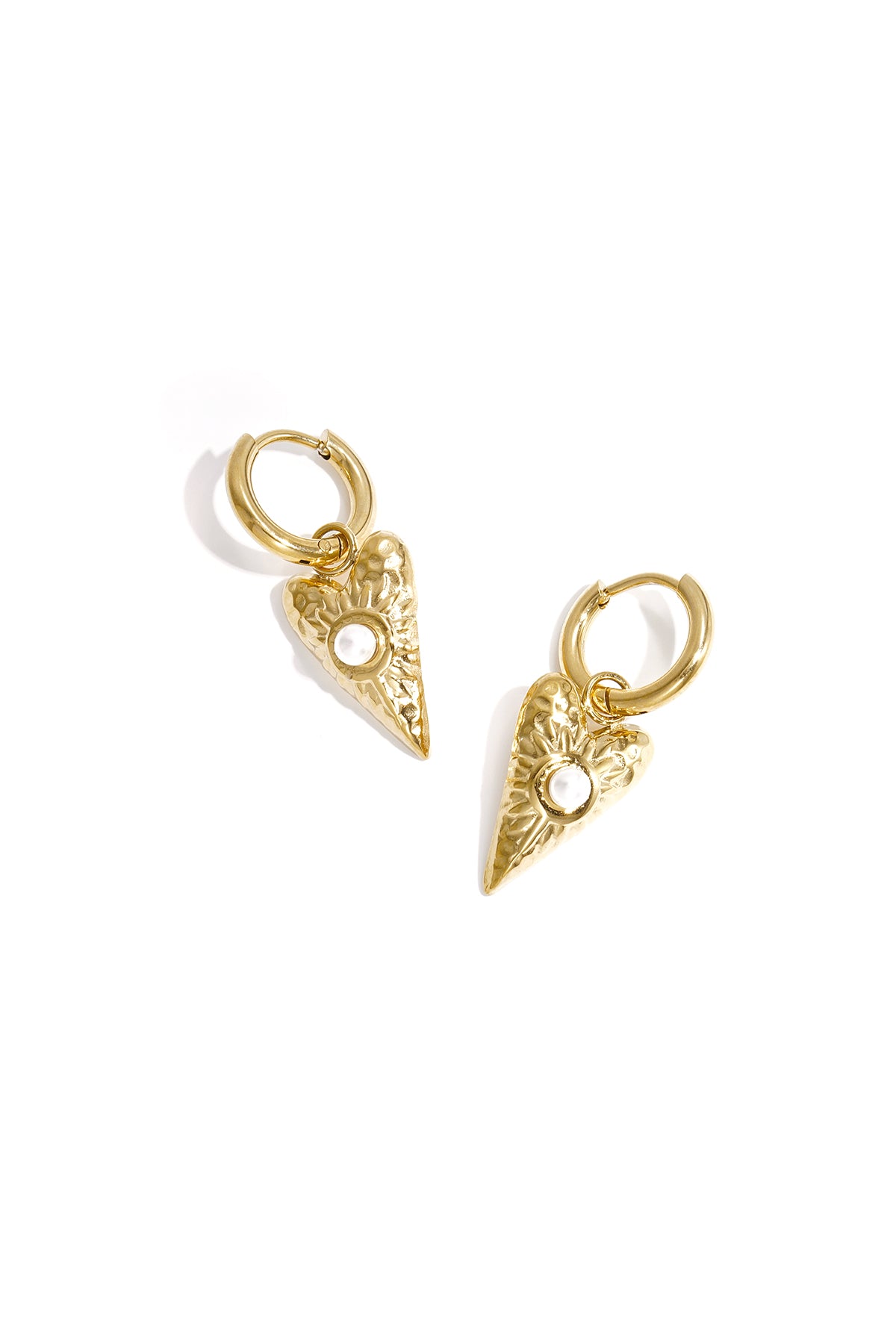 Close-up of gold heart-shaped drop earrings with pearl detail on white background