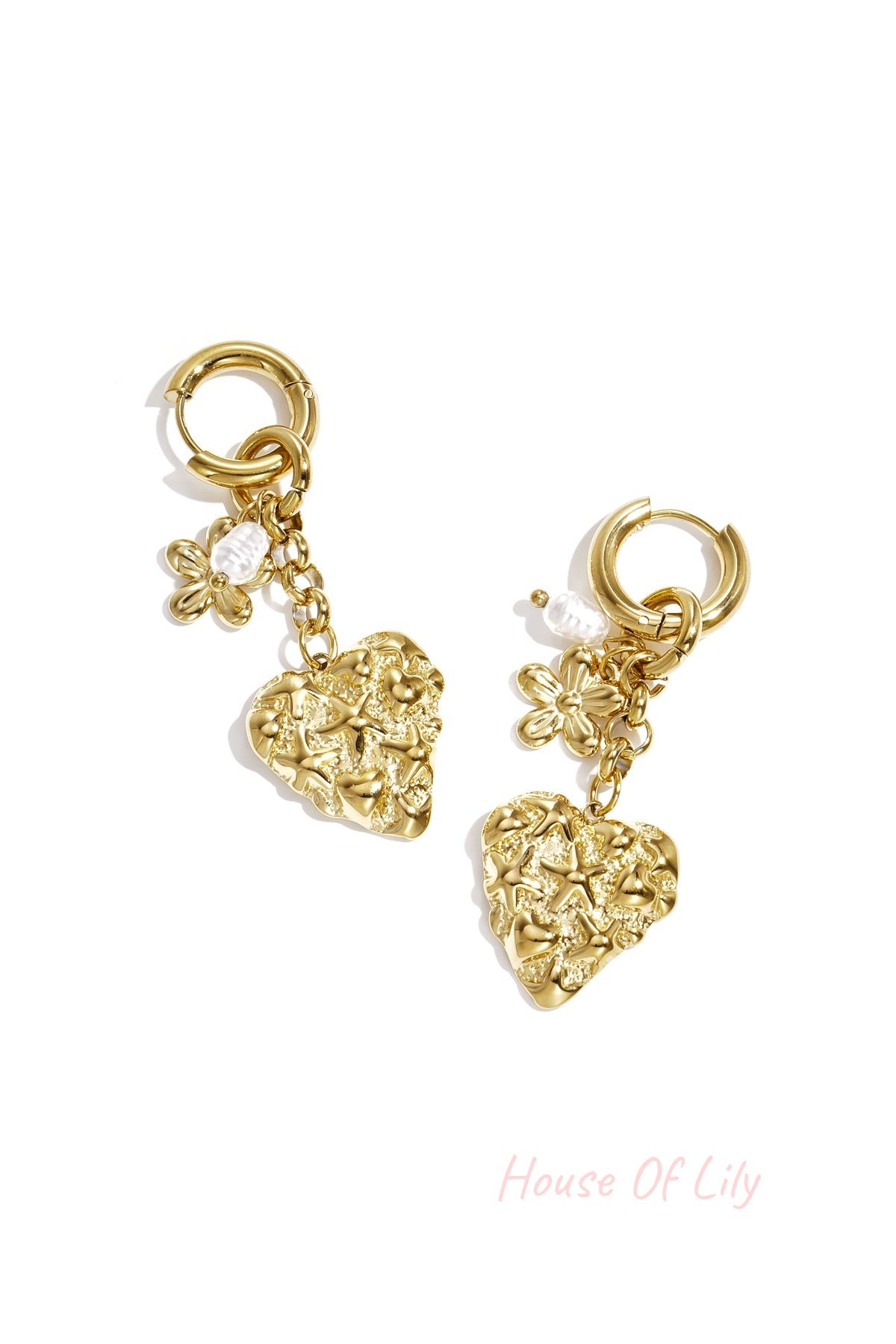 Gold drop earrings featuring textured heart pendants with star and heart motifs, a flower charm, and a small pearl, on white background