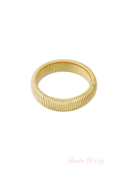 Close-up shot of a gold stretch bracelet with tubular segmented design on white background