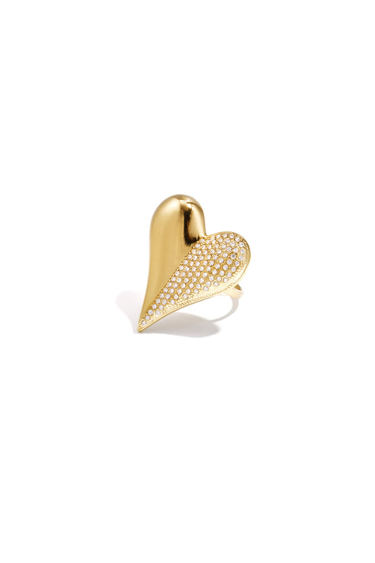 Gold-toned heart-shaped statement ring with rhinestones on one half against a white background