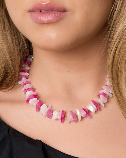 Close-up of a necklace made of tumbled pink and white stone chips separated by small gold beads.