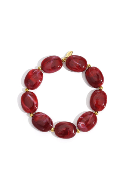 Stretch bracelet featuring deep red, swirled acrylic oval beads separated by small, polished gold-tone metal spacers.