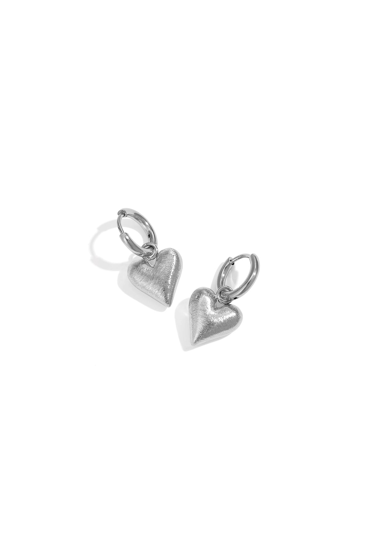 Pair of silver heart charm hoop drop earrings on white background