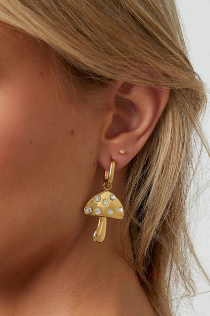 Side profile of a woman wearing the gold mushroom drop earrings, highlighting the shiny gold finish and rhinestone accents