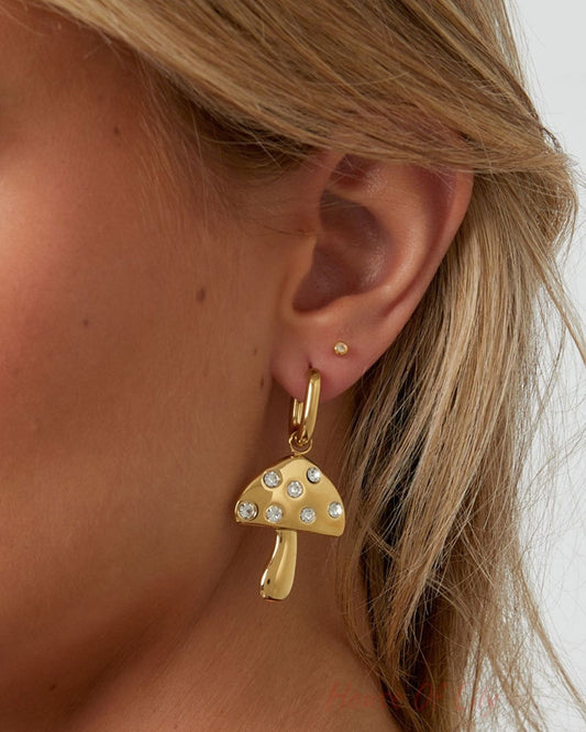 Side profile of a woman wearing the gold mushroom drop earrings, highlighting the shiny gold finish and rhinestone accents