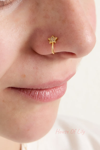 Close-up of woman's nose adorned with gold star nose cuff showing a soft smile