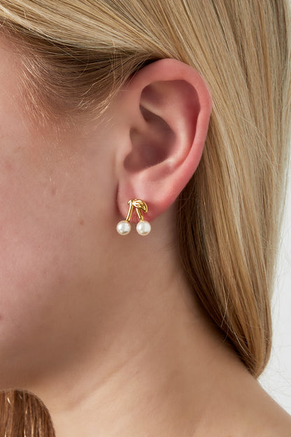 Close-up of cherry clip earrings worn on ear, showing gold-tone stems and pearl details