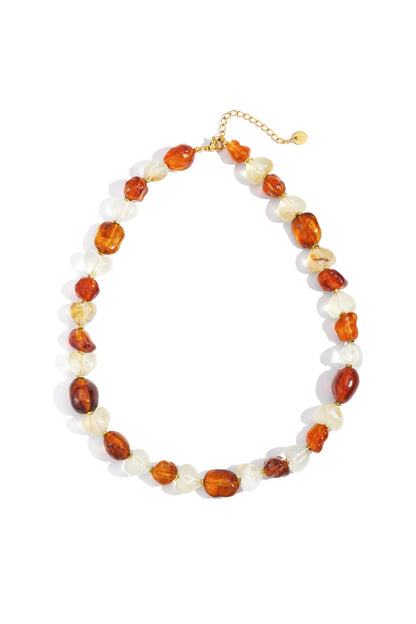 Amber and white acrylic heart and pebble-shaped beads necklace with gold chain extender on white background
