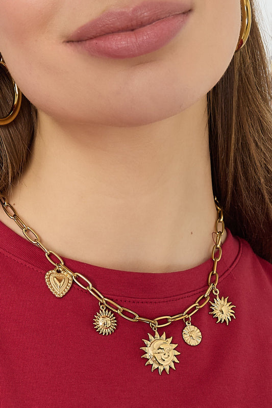 Close-up of woman wearing gold charm necklace featuring sun and heart pendants on red top