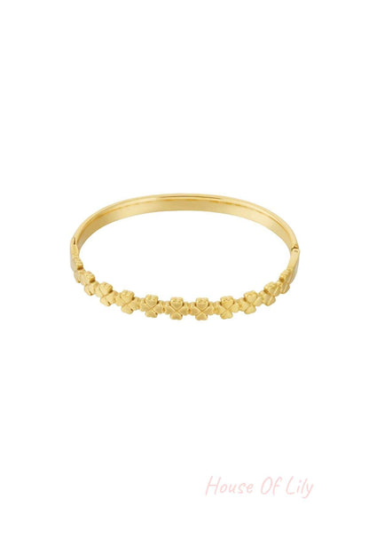 Gold bangle bracelet with linked small four-leaf clover shapes, isolated on white background