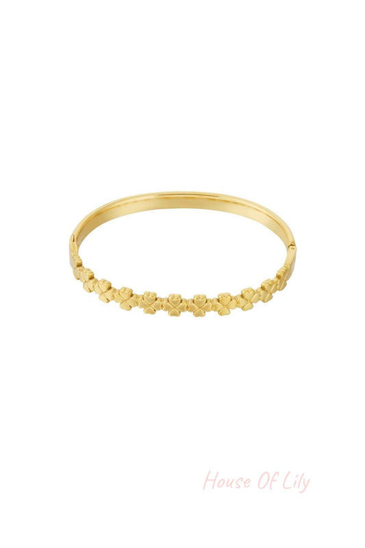 Gold bangle bracelet with linked small four-leaf clover shapes, isolated on white background