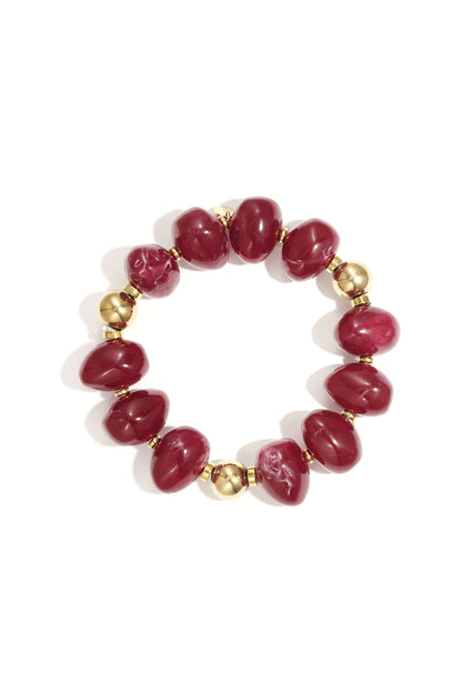 Red marbled resin beaded bracelet with gold beads on white background
