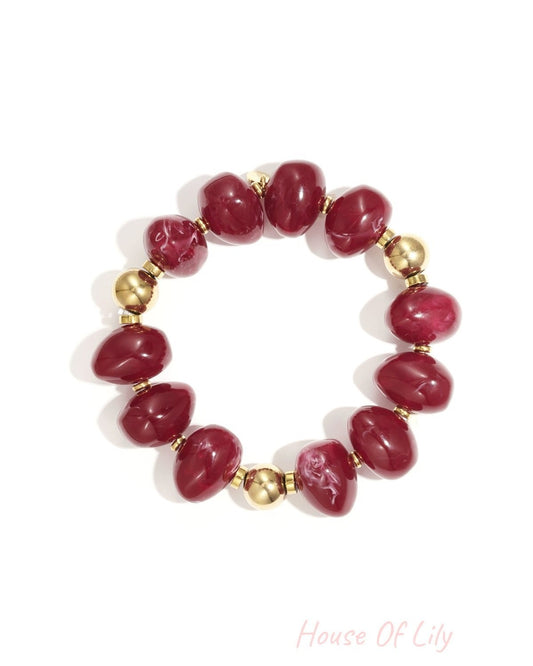 Red marbled resin beaded bracelet with gold beads on white background