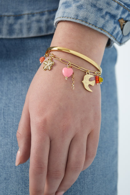 Close-up of golden charm bracelet worn with a blue denim jacket sleeve