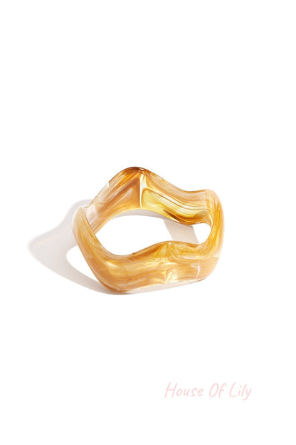 Yellow marbled acrylic bangle with wavy irregular shape on white background