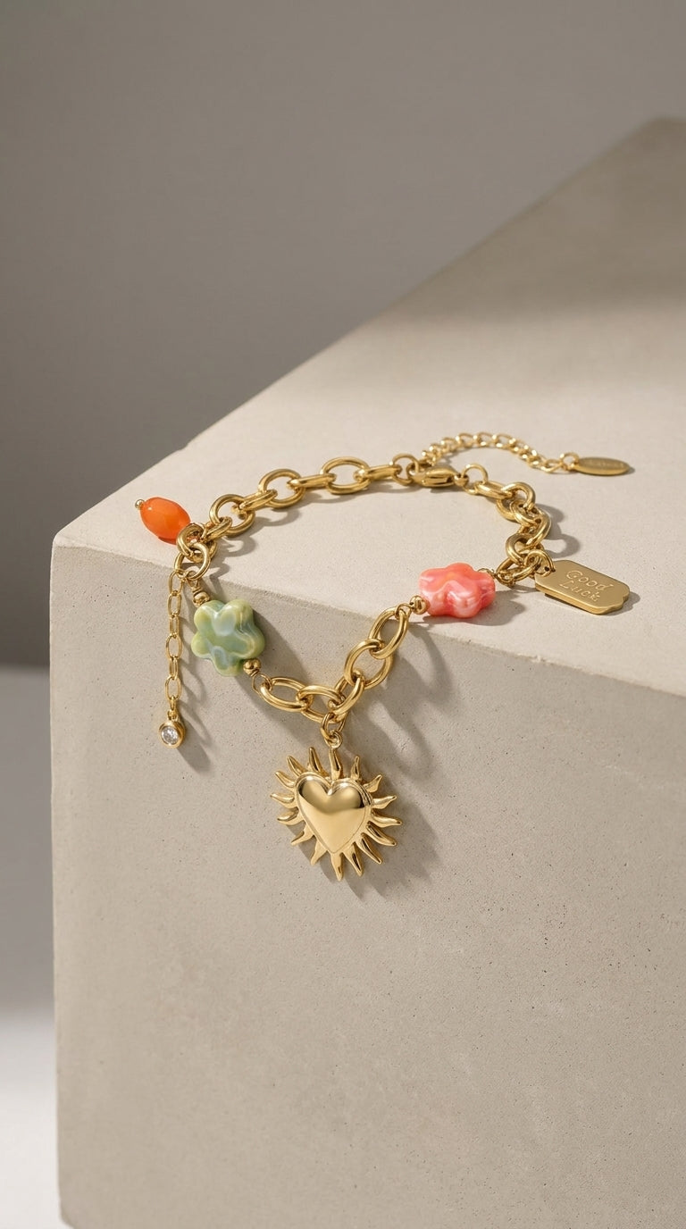 Charm Era Unlocked gold-tone chain bracelet with heart-sun charm, pastel floral beads, and a "Good Luck" tag.