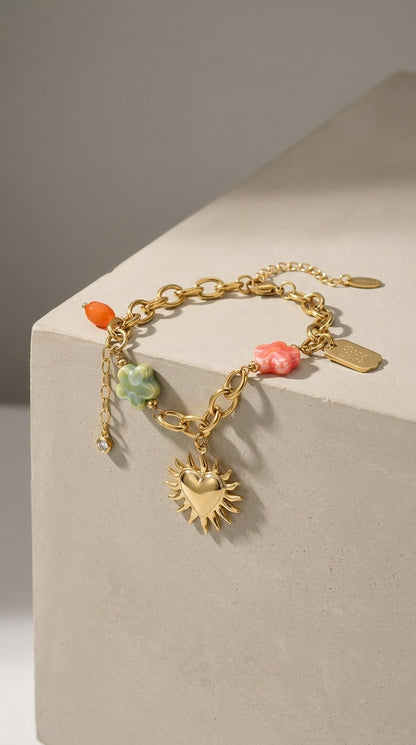 Charm Era Unlocked gold-tone chain bracelet with heart-sun charm, pastel floral beads, and a "Good Luck" tag.