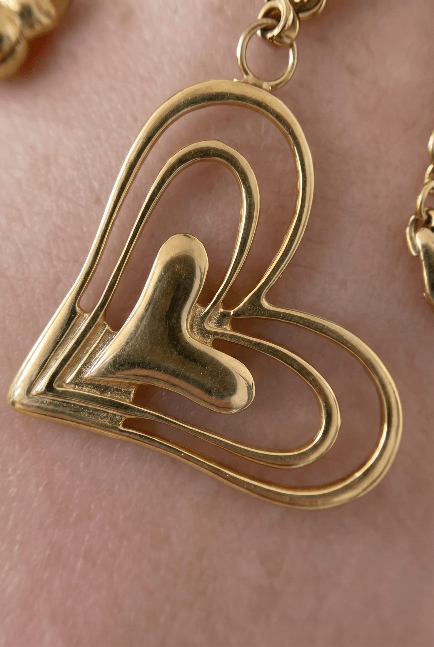 Gold Gilded Heart Charm Bracelet with layered, cutout heart design resting on skin.