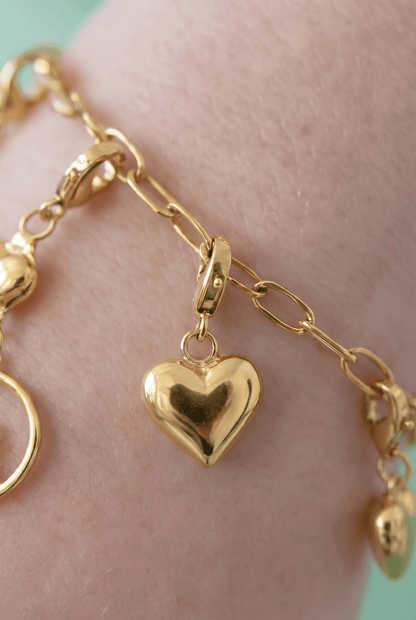 Gilded heart charm bracelet featuring polished gold-tone puffy heart charms on an oval-link chain.